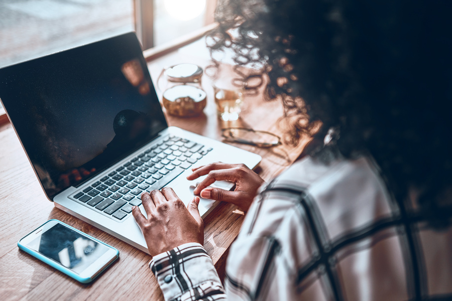 A young girl works in a cafe. Back view. On the monitor screen is a miniature of the starry sky. Creation of the designer.