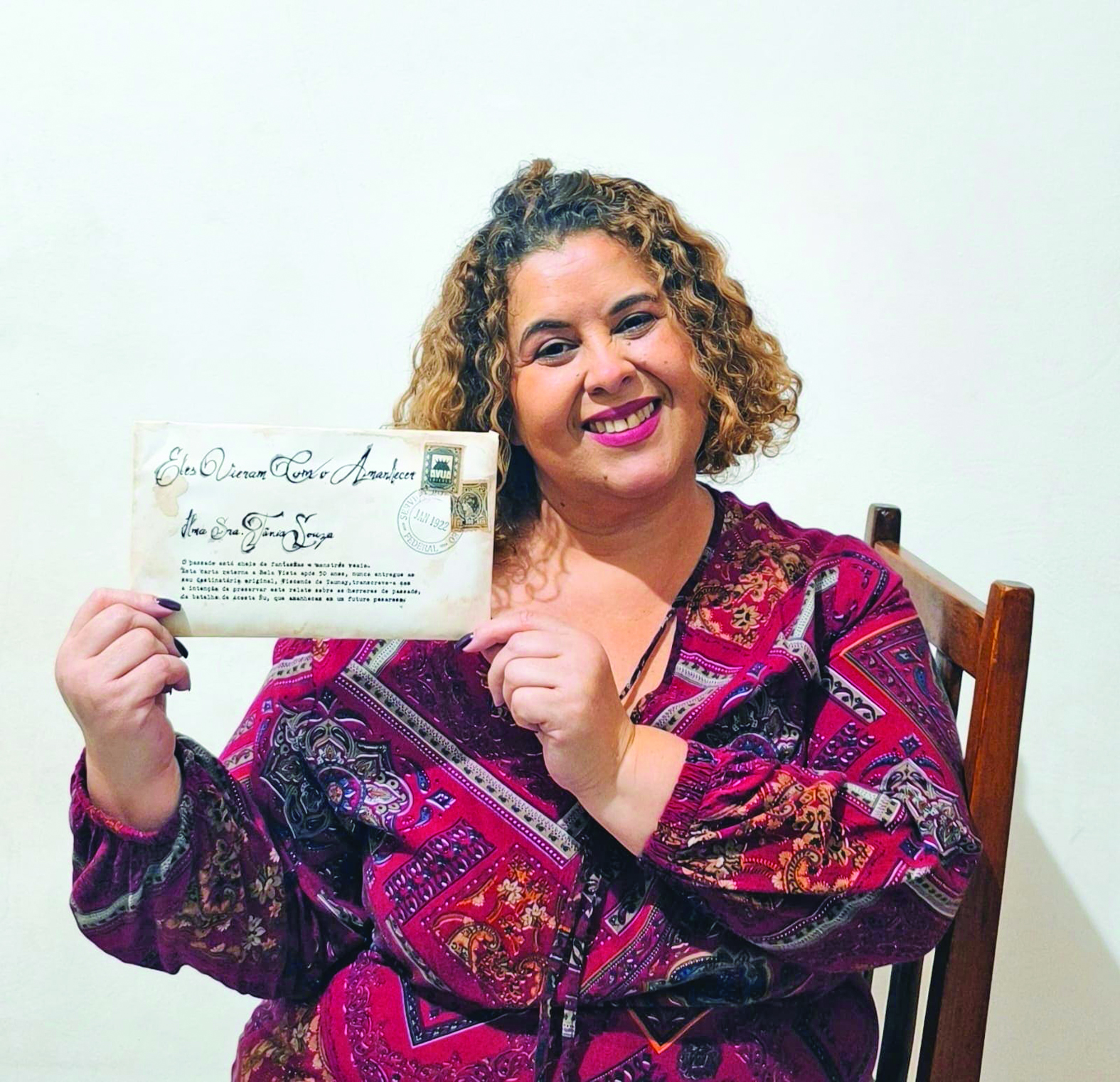 A escritora Tânia Souza posa com sua obra inspirada em cartas e selos antigos - Foto: reprodução