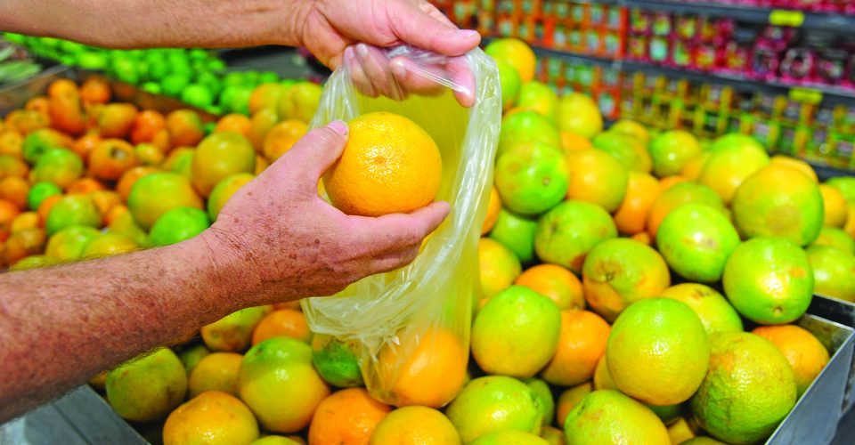 Consumidor escolhendo laranja e suco da fruta expostos para venda - Foto: Nilson Figueiredo