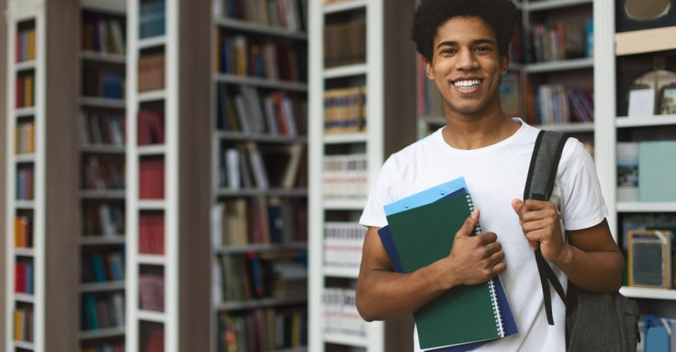 Handsome african american male student posing in campus library, empty space