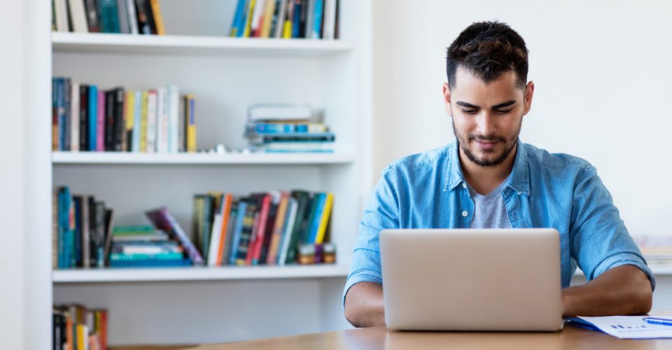 Mexican hipster man working with computer indoor at desk at home