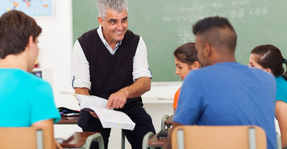 senior high school teacher teaching group of students in classroom