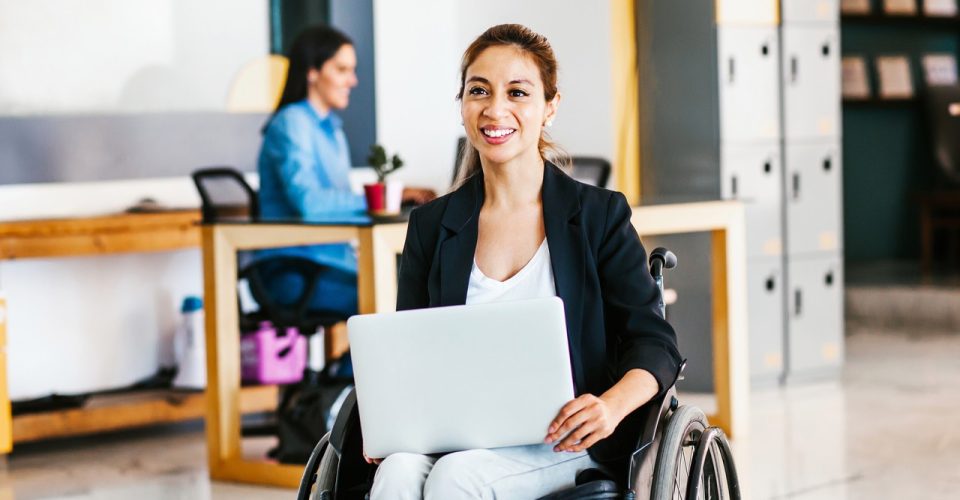 Mexican woman in wheelchair with her colleagues at workplace in
