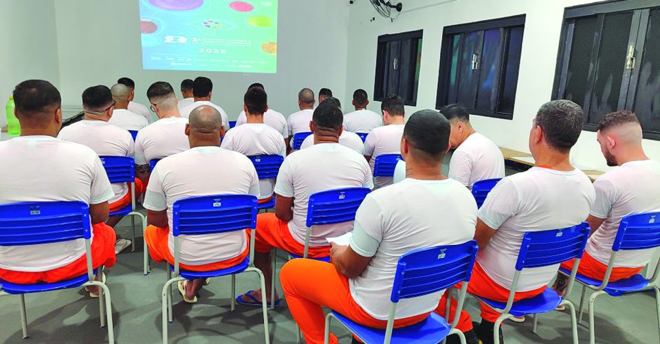 Interna D.G. faz anotações e, internos assistem à exibição  de um filme - Foto: Comunicação Agepen/Divulgação