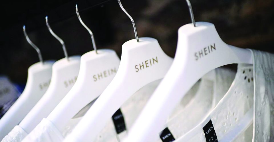 Blusas da loja Shein
penduradas em cabides (Christophe Archambault/FolhaPress)