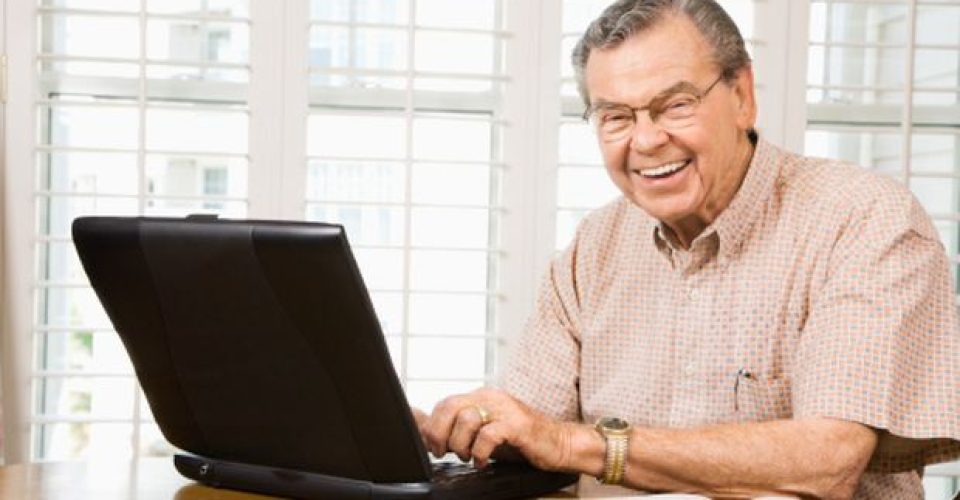 Mature Caucasian man typing on laptop in home.